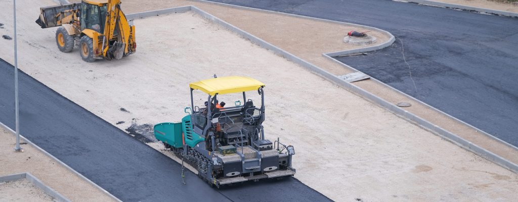 worker-asphalt-paving-machine-while-lays-asphalt-excavator-construction-site-top-view